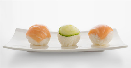 Little Nigiri Sushi or Temarizushi with Salmon and Cucumber on Light Background Close Up. Rice Balls...