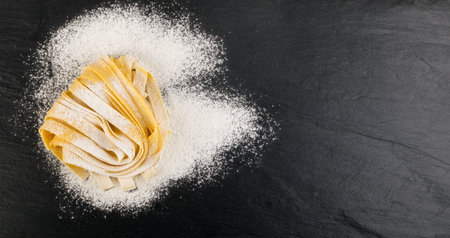 Raw yellow italian pasta pappardelle, fettuccine or tagliatelle close up. Egg homemade noodles...