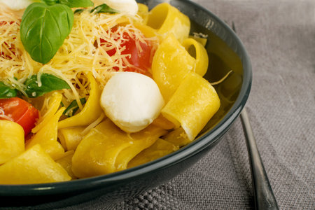 Yellow cooked pasta pappardelle, fettuccine or tagliatelle in black bowl close up. Egg homemade...