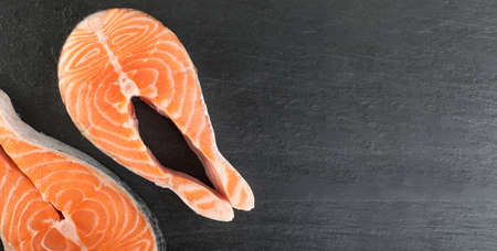 Slice of Raw Pink Salmon Steak for Restaurant Menu Close Up on Black Stone Background Background. Thick Piece of Fresh Red Fish, Chum or Trout Top Viewの写真素材