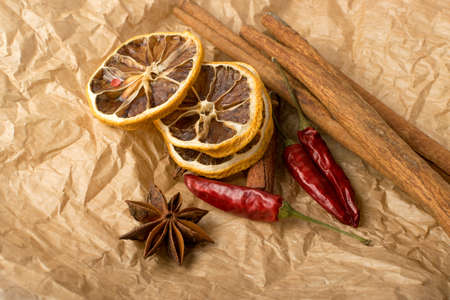 Dry spices for mulled wine with dehydrated sliced citrus on vintage kraft pack paper background. Winter oriental condiments such as dried lemon, cinnamon, red pepper and anise starsの写真素材