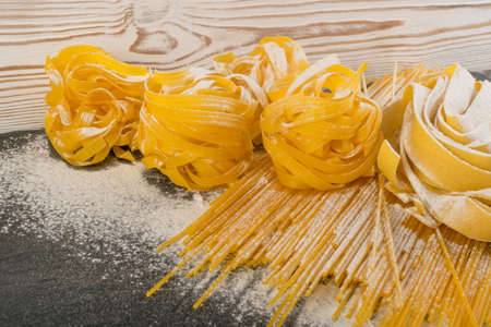 Raw yellow italian pasta pappardelle, fettuccine or tagliatelle close up. Egg homemade noodles cooking process, long rolled macaroni or uncooked spaghettiの写真素材