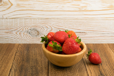 Fresh Beautiful Strawberry in Bowl on Old Vintage Wooden Background with Copyspace. Wood Table Desk Board Texture with Ripe Berryの写真素材