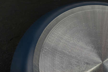 Macro photo of frying pan metallic bottom texture or underside on black backgroundの写真素材