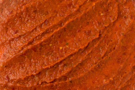 Smeared ajvar or pindjur orange vegetable spread texture made from bell peppers, eggplants and oil. Marinara sauce smear, salsa, chutney or lutenica background or pattern top viewの写真素材