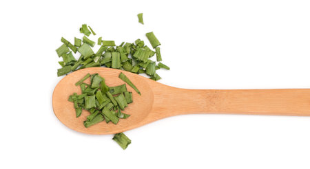Dry chive or dehydrated green onion in a wooden spoon isolated on white background top view. Chopped...