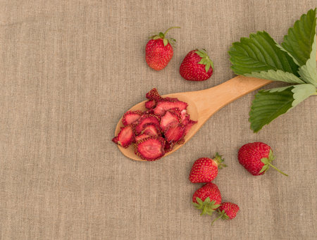 Group of home cooked dehydrated dry strawberries on rustic burlap background top view. Dried...