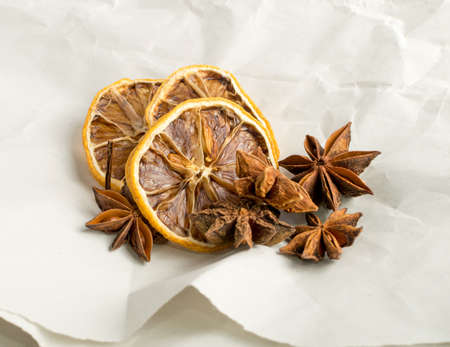 Dry spices for mulled wine with dehydrated sliced citrus on vintage kraft pack paper background. Winter oriental condiments such as dried lemon, cinnamon and anise starsの写真素材