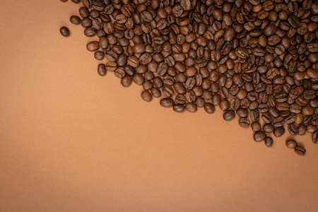 Dark whole coffee beans on brown background with copyspace. Roasted coffe grains for menu, banner template, wallpaper or recipe image designの写真素材