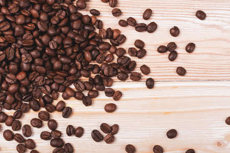 Dark brown whole coffee beans on wood background with copyspace. Roasted coffe grains on wooden texture for menu, banner template, wallpaper or recipe image designの写真素材
