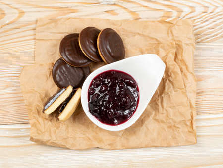 Jaffa cake or biscuit cookie filled with natural jam. Round chocolate covered cookies with fruit marmalade or jelly on wood table backgroundの写真素材