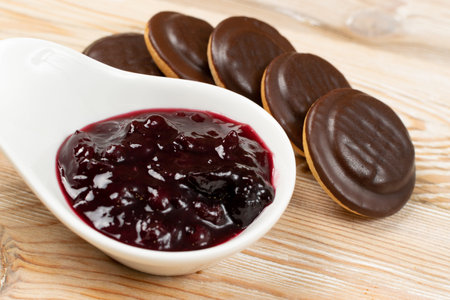 Jaffa cake or biscuit cookie filled with natural jam. Round chocolate covered cookies with fruit marmalade or jelly on wood table backgroundの写真素材