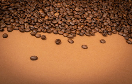 Dark whole coffee beans on brown background with copyspace. Roasted coffe grains for menu, banner...