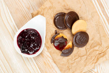 Jaffa cake or biscuit cookie filled with natural jam. Round chocolate covered cookies with fruit marmalade or jelly on wood table backgroundの写真素材