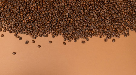 Dark whole coffee beans on brown background with copyspace. Roasted coffe grains for menu, banner...