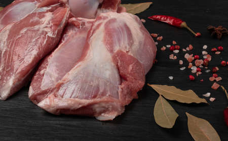 Fresh raw mutton shoulder meat with bone on black stone plate background. Large piece of sheep fillet or filet closeupの写真素材