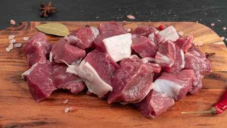 Raw chopped lamb fillet, diced tenderloin or cubed mutton sirloin meat on black stone plate...