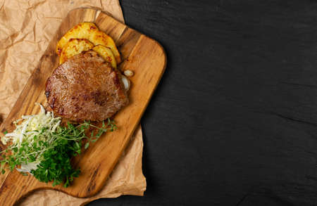 Hot grilled chivas beef steak with coleslaw, fried potatoes and greens on wood cutting board. Well done beefsteak or bbq entrecote meat in rustic styleの写真素材