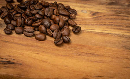 Dark brown whole coffee beans on wood background with copyspace. Roasted coffe grains on wooden texture for menu, banner template, wallpaper or recipe image designの写真素材
