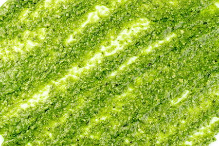 Pesto spread pattern, texture on white background. Green italian homemade spilled sauce made of...