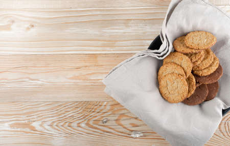 Thin oatmeal cookies or healthy cereal oat crackers with chocolate. Crispy anzac biscuit cookie with oat flakes on rustic table background top viewの写真素材