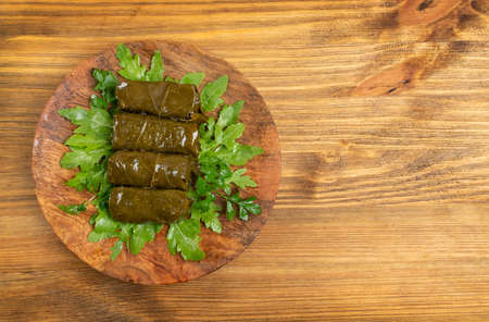Traditional Turkish Dolma, Sarma or Dolmades on Wooden Plate Top View with Copyspace. Mediterranean Dish Dolmadakia or Tolma with Rice and Grapes Leaves Closeupの写真素材