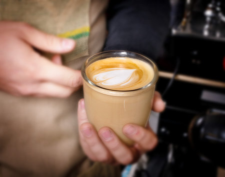 Male hands preparing latte or cappuccino art in coffeeshop closeup. Barista makes coffee with milk in coffee shop cafe close upの写真素材