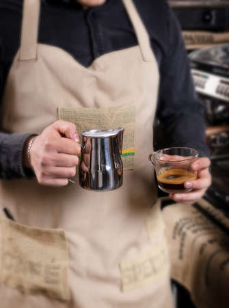 Male hands preparing latte or cappuccino art in coffeeshop closeup. Barista makes coffee with milk in coffee shop cafe close upの写真素材
