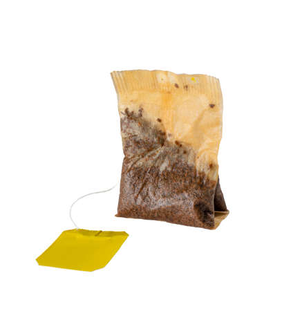 Used wet teabag isolated on white background closeup. Macro shot of old tea bag with blank paper labelの写真素材