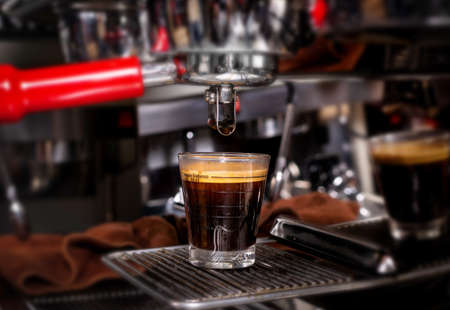 Macro shot of preparing espresso on professional coffee machine. Making coffee in espresso shot in coffeeshop or cafe closeupの写真素材