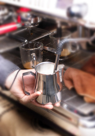 Macro shot of whipping milk for latte, cappuccino or mocha on professional coffee machine in...