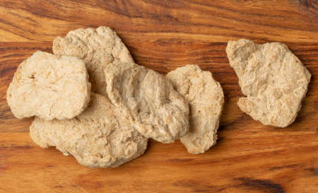 Raw dehydrated soy meat or soya chunks on wood background top view. Texturized vegetable protein, also known as textured soy protein or TSPの写真素材