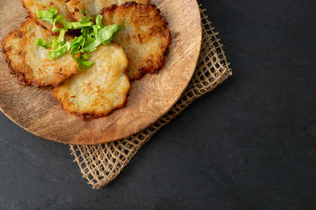 Potato pancakes on wood plate. Fried grated vegetable pancakes or potato fritter with onion on rustic backgroundの写真素材