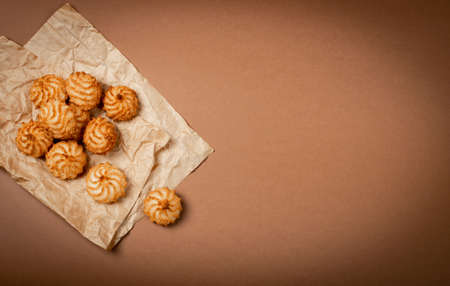 Natural baked coconut cookies or coconut macaroons on brown paper background. Homemade diet biscuits with coco chips on parchment top view, copy spaceの写真素材