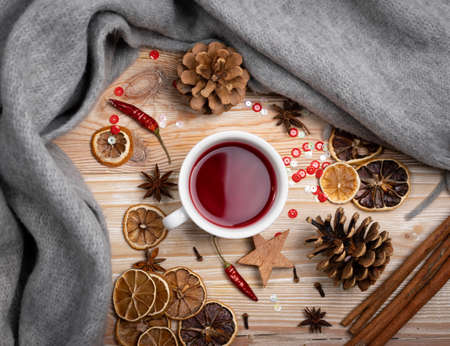 Cranberry or Hibiscus Drink, Warming Beverage. Hot Red Winter Tea with Spices on Wooden Table Background with Warm Grey Scarf Top Viewの写真素材
