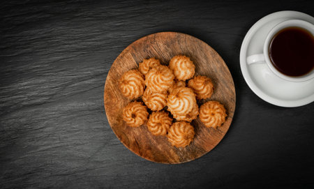 Natural baked coconut cookies or coconut macaroons on wooden plate with tea or coffee. Homemade diet...