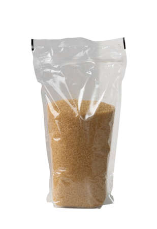 Plastic bag with brown sugar isolated on white background. Raw unrefined cane sugar heap side viewの写真素材
