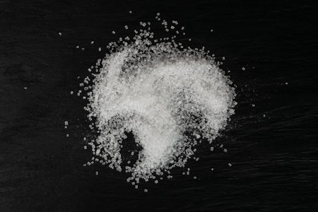 Heap of big sugar crystals on black background close up. Macro shot of sucrose crystals, sea salt...