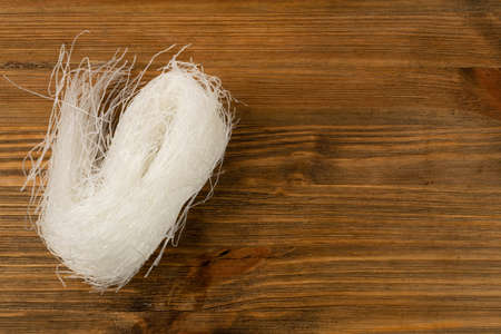 Raw dry rice noodles on wooden table background top view. Traditional asian rice vermicelli with copy spaceの写真素材