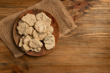 Raw dehydrated soy meat or soya chunks on wood background top view. Texturized vegetable protein,...