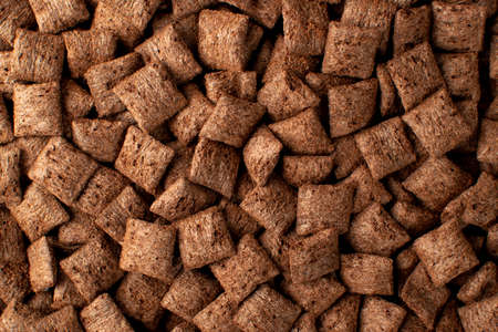 Chocolate pillows background texture. Brown choco cereal pads pattern, crispy corn flakes wallpaper, healthy sweet snack for breakfast mockup with copy space top viewの写真素材