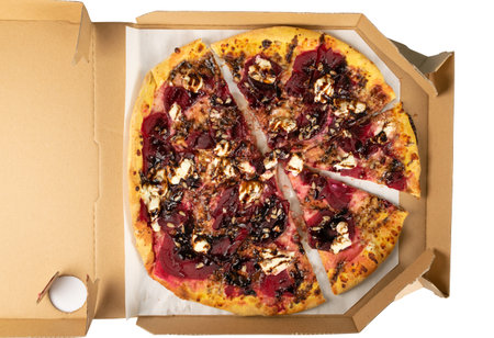 Vegetarian beetroot pizza with cheese, sliced pickled beet, nuts and sunflower seeds in cardboard delivery box top view. Sweet alternative vegetable flatbread in open pizzeria package closeupの写真素材