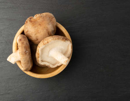 Pile of fresh shiitake mushrooms on black stone slate with copy space. Raw shitake, healthy organic asian fungi top viewの写真素材