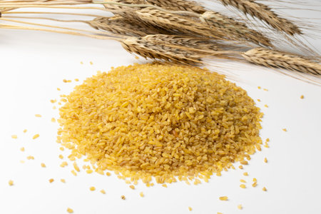 Bulgur heap isolated on white background. Pile of raw bulghur, dry cracked parboiled wheat groats,...