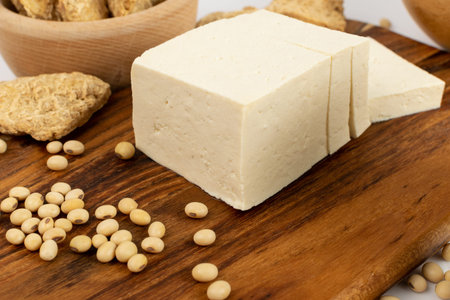 Fresh tofu cheese or vegan cheese on rustic background side view. Sliced soya bean curd, soy protein...