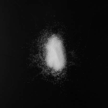 Heap of White Powder of Baking Soda, Clay or Bentonite on Black Background. Powdered Chemicals as Calcium, Gypsum or Plaster Top Viewの写真素材