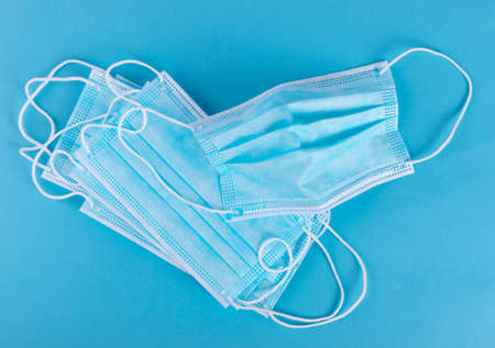 Medical mask on blue background. Surgical masks cover mouth and nose. Disposable medic clothing item, hospital equipment, corona virus face protection conceptの写真素材