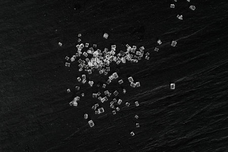 Big sugar crystals on black background close up. Macro shot of sucrose crystals, sea salt rock or...