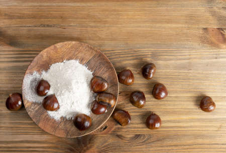 Chestnut flour with edible sweet whole chestnuts close up. Raw healthy delicious chestnut powder, autumn and Christmas veggie food top viewの写真素材