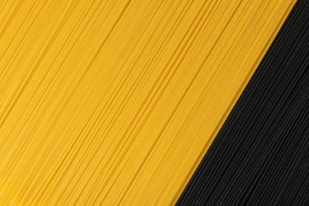 Raw black homemade spaghetti mockup on dark background. Dry black and yellow egg noodles texture, macaroni pattern. Dark uncooked italian spaghetto top viewの写真素材